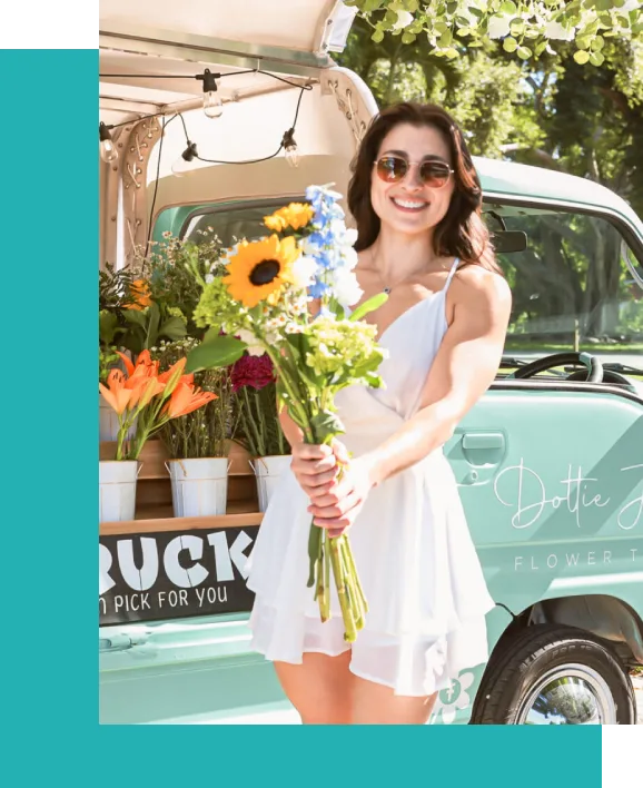 A woman holding flowers in front of a truck.