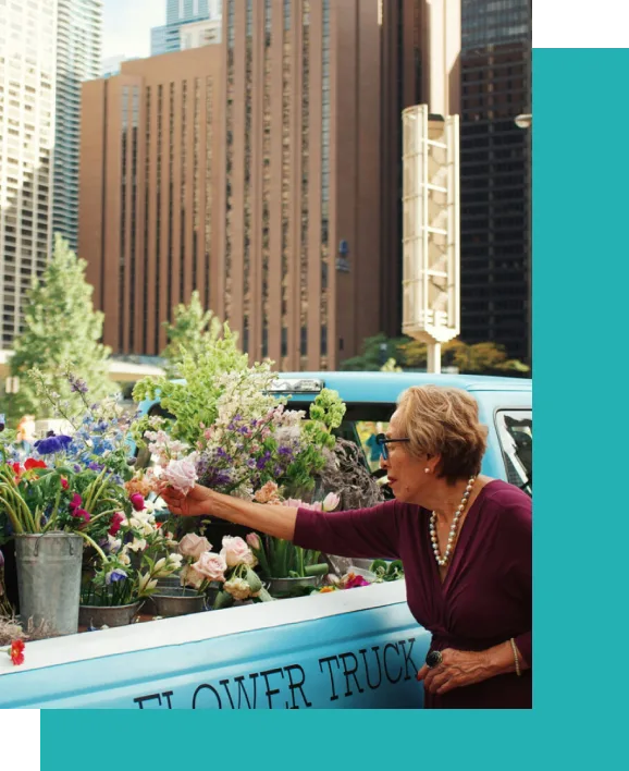 A woman standing in the back of a truck with flowers.